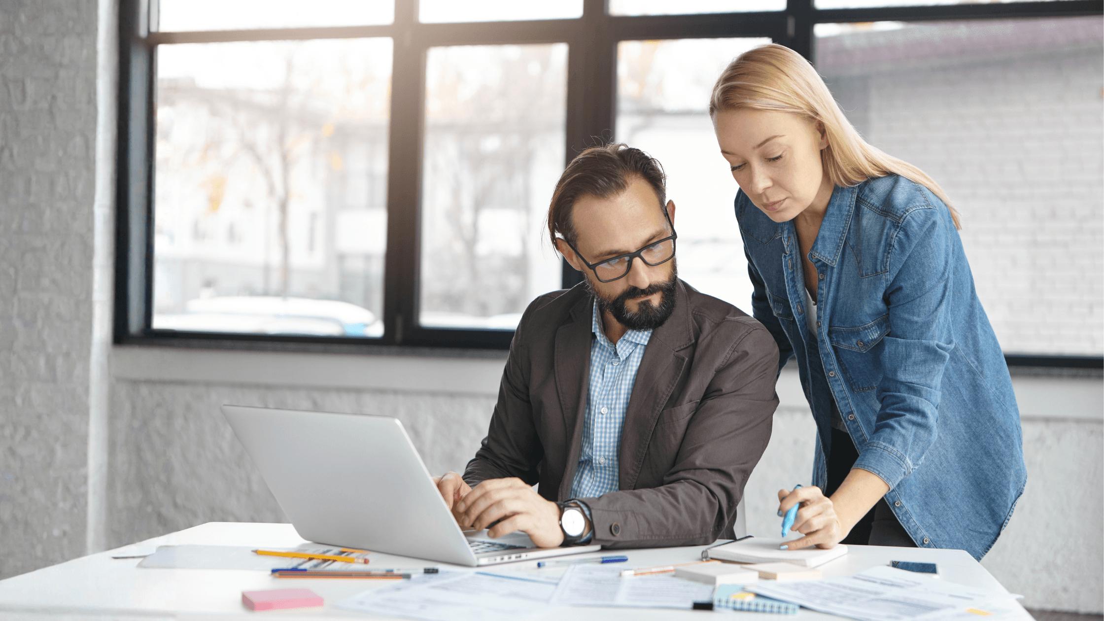Two accounting firm partners reviewing financial documents and laptop data during a tax planning or CPA advisory