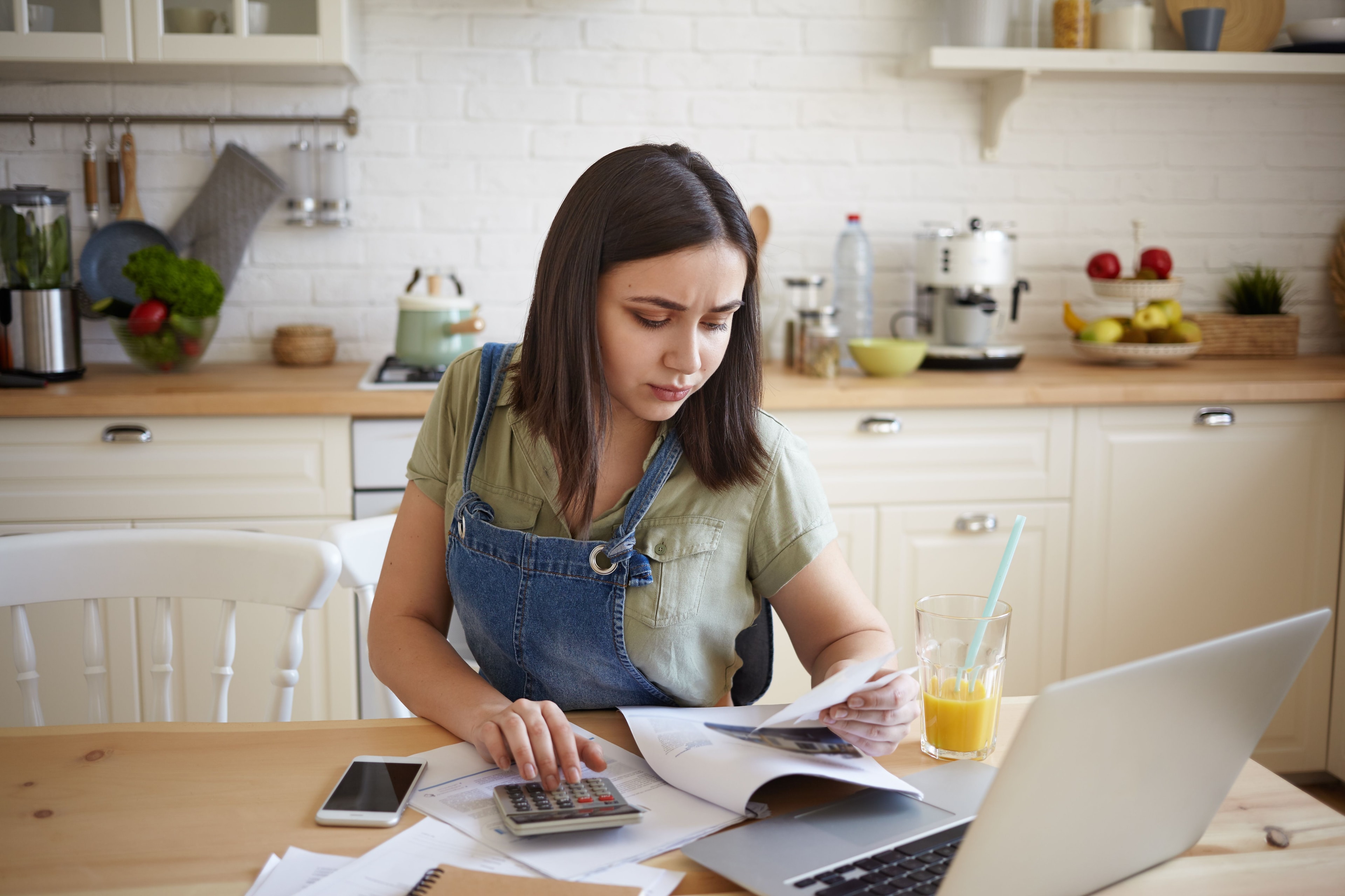 Content creator computing taxes at home office using laptop, receipts, and calculator for freelance income reporting