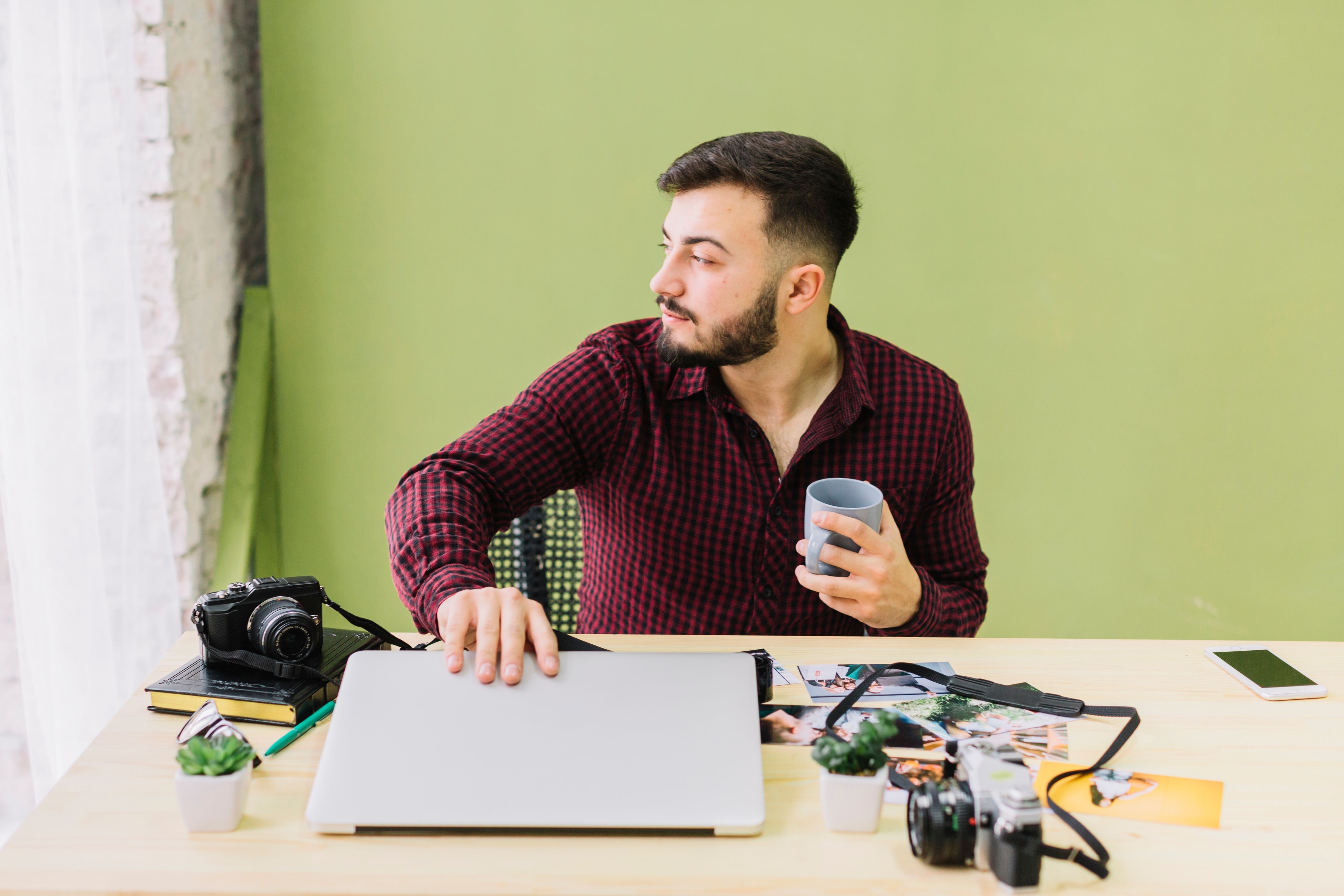 Creator at a desk with camera gear and laptop, pausing to reflect on next business steps before switching to an S corp.