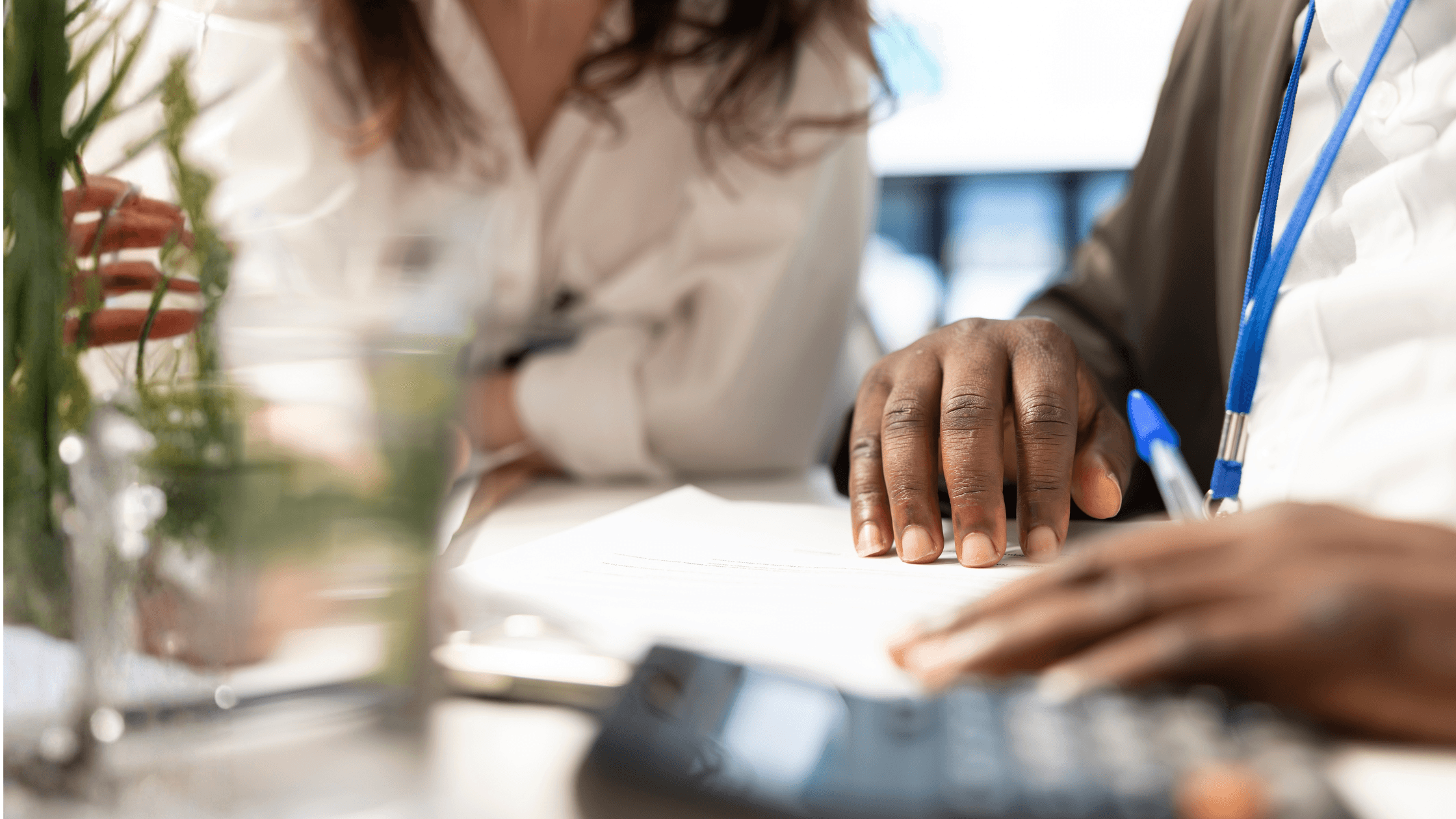 Close-up of two business professionals reviewing paperwork during a financial advisory meeting, representing client education, accounting guidance, and proactive business planning.