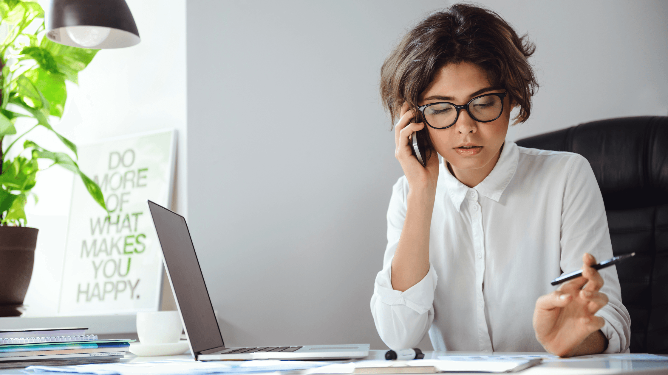 Young accountant on the phone at her desk reviewing paperwork, laptop open, illustrating a practical tax planning checklist and the client tax events that should trigger a CPA check-in.